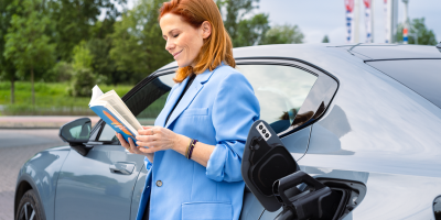 Vrouw leest een boek tijdesn het laden van haar electrische auto