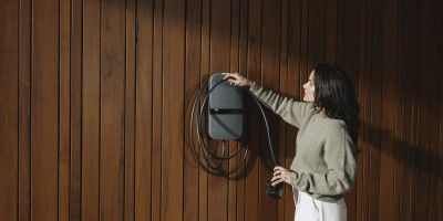 vrouw rolt de kabel van haar thuislader rond de Peblar lader